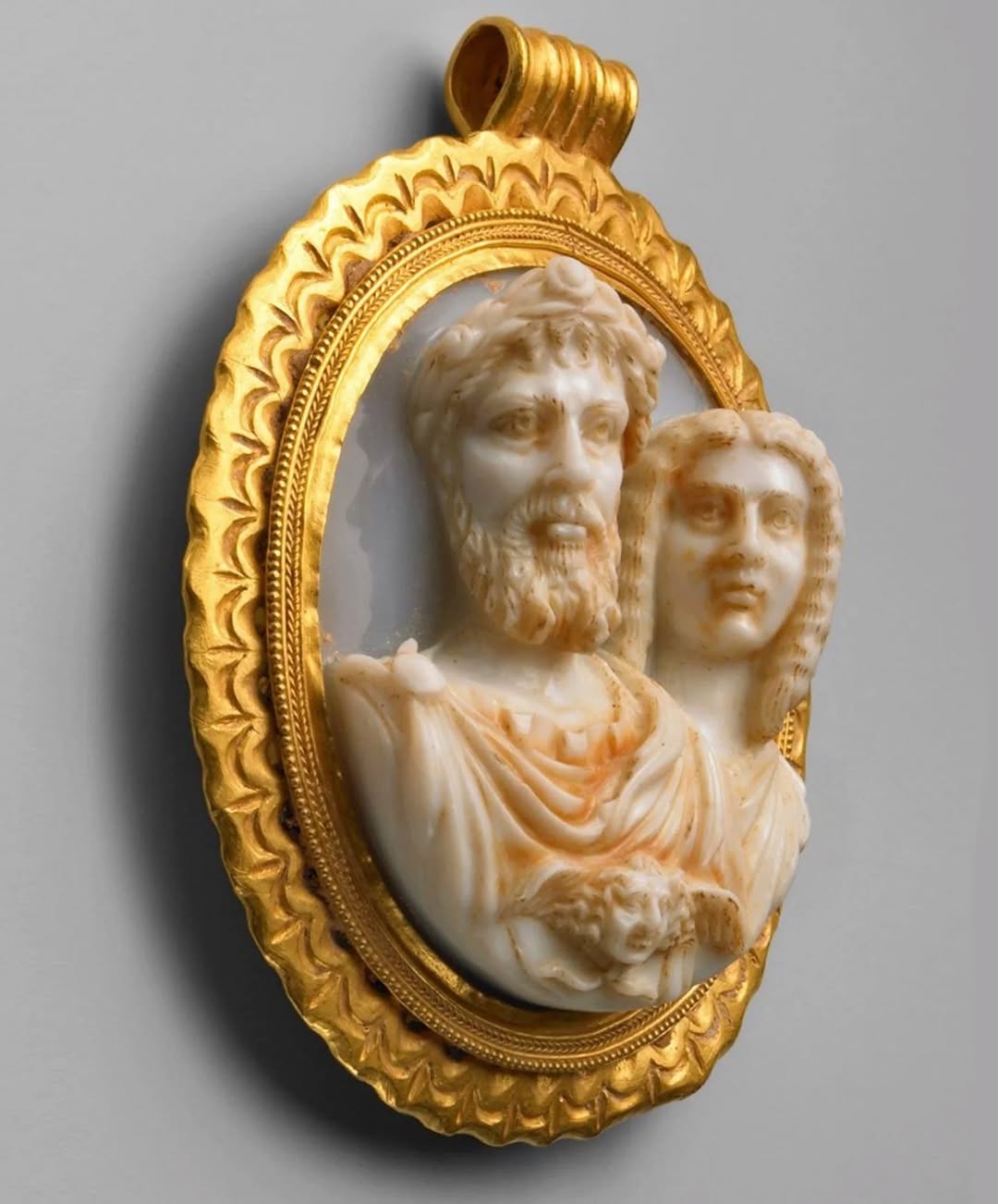 An ancient Roman sardonyx cameo depicting Emperor Septimius Severus and his wife Julia Domna, circa 207-211 CE. The cameo was set in a richly decorated frame within a gold pendant 