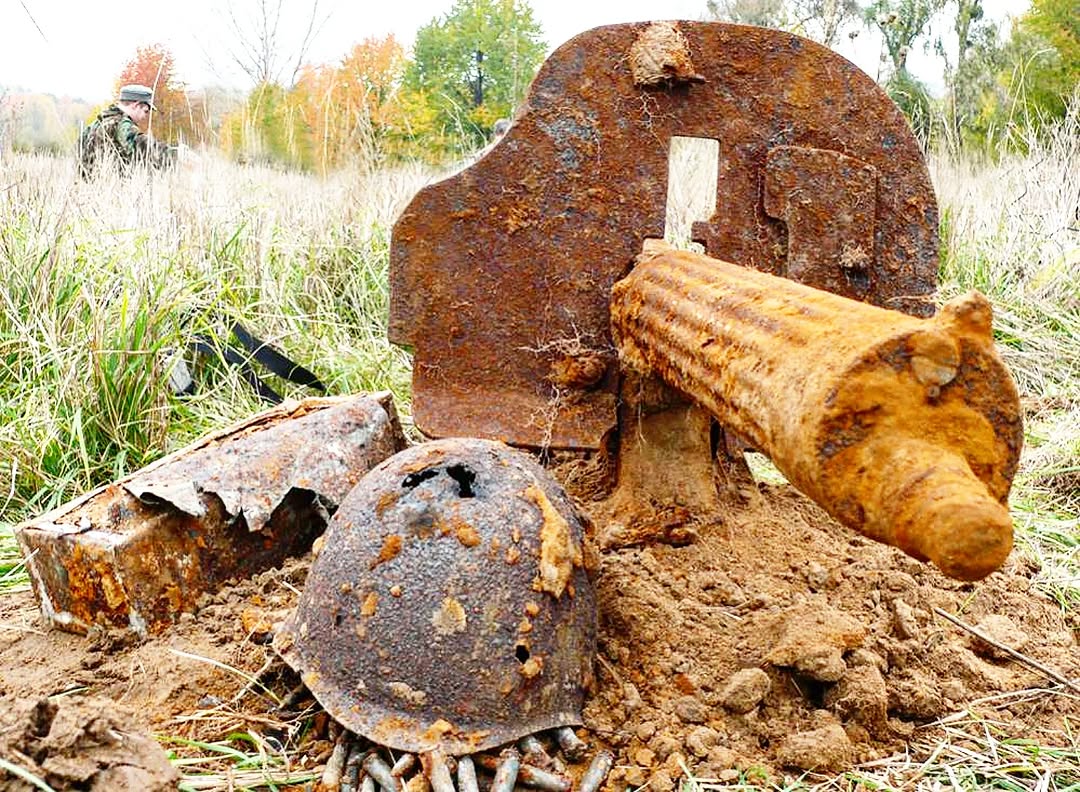 Military artifacts recovered during excavations at a site of battles from the Great Patriotic War. In the center of the composition is a heavily corroded barrel of a Maxim machine 